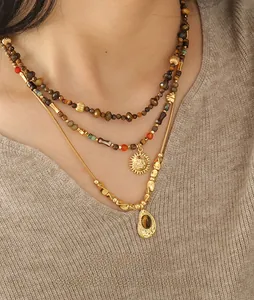 Detail of bohemian layered necklace with beaded chains and a golden sun pendant