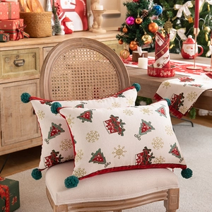 Close-up of beige Christmas throw pillows with green tassels on a rustic rattan chair