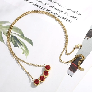 Dettaglio della collana dorata con quattro pietre rosse e chiusura a moschettone