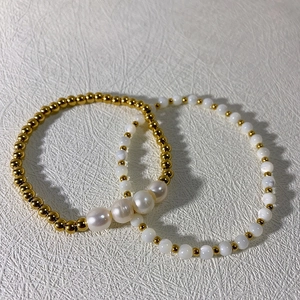 Ensemble de bracelets élégants en perles dorées et blanches sur fond texturé chic