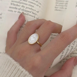 Macro detail of gold vintage ring with white shell inlay and heart cross engraving