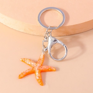 Macro shot of an orange resin starfish keychain with shimmering glitter on a wooden base