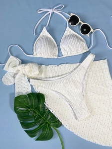 Detailansicht des weißen Bikini-Sets mit 3D-Punktstruktur und Wickelrock am Strand