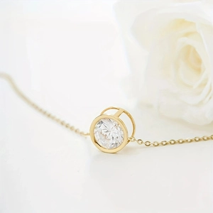 Layered 18k gold necklace with brilliant round zircon pendant on white rose background