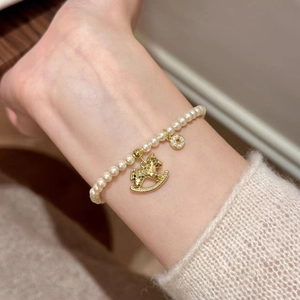 Elegant pearl bead bracelet with golden rocking horse and zircon pendant on wrist