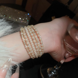Close-up of double-layer pearl and rhinestone bracelet worn by a model in social setting