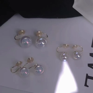 Macro detail of iridescent pearl earrings featuring silver adjustable screw clips
