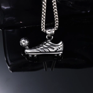 Retro silver football boot pendant necklace with beaded chain on black mirror background