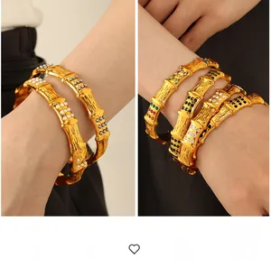 Detailed view of gold bamboo bracelets with colorful rhinestones and pearls on a wrist