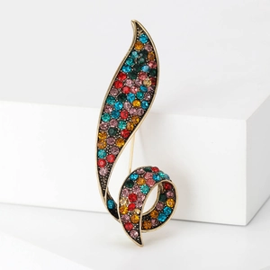 Macro view of vintage gold leaf brooch with colorful rhinestones on a white stand