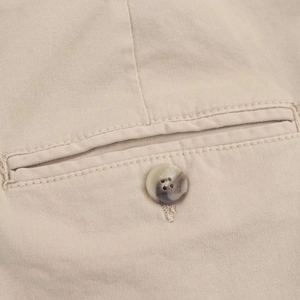 Close-up of khaki cotton fabric texture with resin button and reinforced stitching