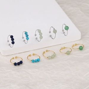 Detail of gold and silver open rings set with four colorful pearl beads in various shades