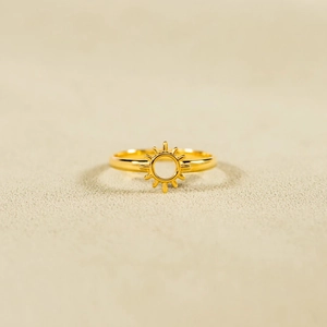 Anello sole minimalista in argento S925 dorato su uno sfondo di sabbia di spiaggia