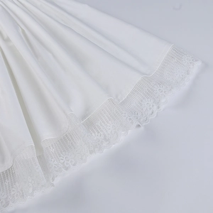 Detalle del dobladillo de encaje blanco y bordado en un vestido con mangas abullonadas