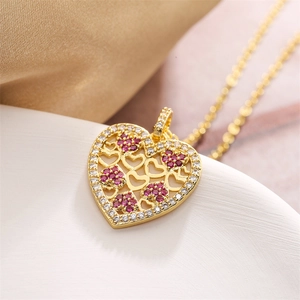 Close-up of golden heart pendant necklace with red zircon stones on a white background