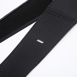Macro view of black pebbled leather belt detail with fine stitching and rectangular slot