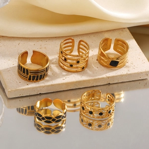 5-piece set of minimalist gold rings with black enamel oil drip on stone background
