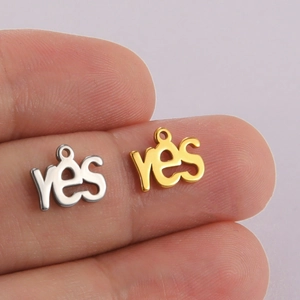Gold and silver YES letter pendants in stainless steel shown on a fingertip