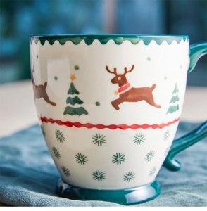 Close-up of a Christmas ceramic mug with reindeer patterns and dark green handle