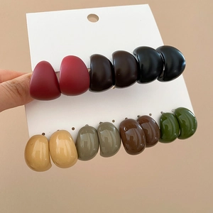 Close-up of colorful resin acrylic C-shaped earrings set on a white display card