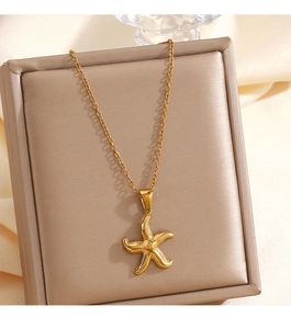 Détail d'un collier pendentif étoile de mer dorée sur un coffret à bijoux beige de luxe