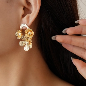 Gros plan détaillé de boucles d'oreilles fleurs dorées vintage au fini métal martelé