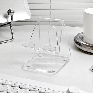 Close-up of clear acrylic phone stand featuring a built-in hole for charging cables