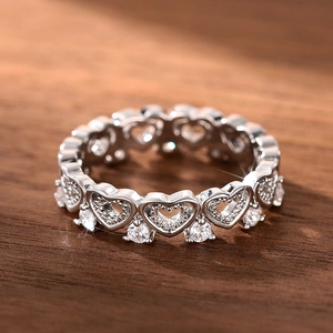 Macro shot of silver heart-shaped openwork ring with sparkling cubic zirconia on wood