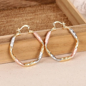 Three-tone geometric textured gold silver and rose gold hoop earrings on wood