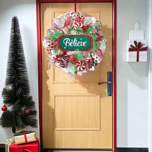 Festive Believe Christmas wreath with red and white mesh ribbons on a wooden door