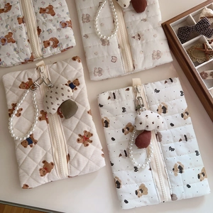 Detailed view of quilted cotton pouches featuring bear and floral prints with pearl straps
