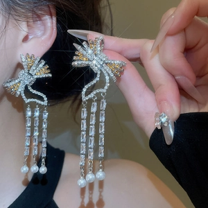 Macro detail of bow-knot pearl tassel earrings with shimmering crystals and silver pins