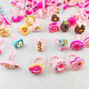 Détails de bagues roses pour enfants avec formes de desserts comme gâteaux et donuts