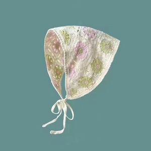 Close-up of handmade crochet headscarf with pink floral patterns on cream knit fabric