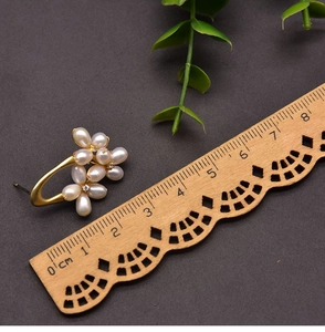 Detail shot of pearl flower earrings with matte gold finish measuring 2.5 cm long