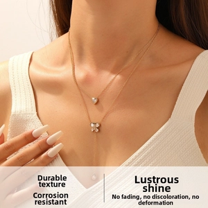 Close-up of double-layered gold necklace featuring a heart and butterfly pendant with tassels