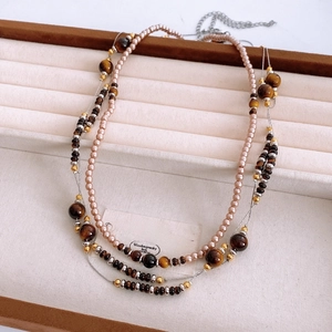 Detail of vintage layered necklace with tiger eye beads and pearls on jewelry tray