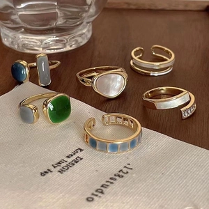 Detailed macro view of vintage gold rings with emerald green stones and opal inlays