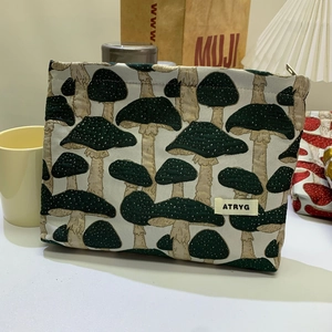 Close-up of beige mushroom jacquard makeup bag with ATRYG label on a lifestyle desk