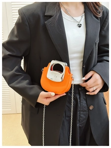 Close-up of orange patent leather mini bag with silver metal handle and chain strap