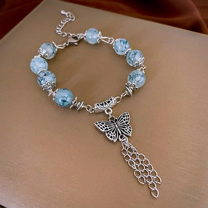 Detail of light blue marbled beads with hollow butterfly pendant and tassel fringe