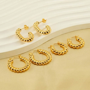 Three pairs of vintage twisted gold hoop earrings on a velvet background and white display
