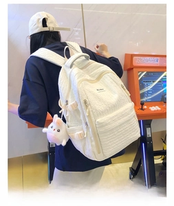 Détail du sac à dos blanc avec texture gaufrée et breloque lapin en peluche doux