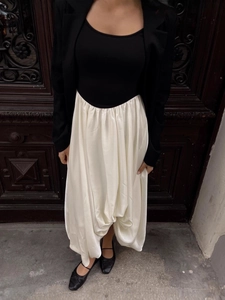 Fashionable contrast paneled outfit with slim black blazer and satin cream pleated skirt