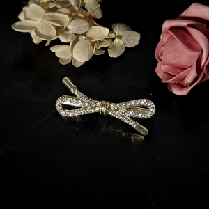 Detailed view of elegant gold-toned bow brooch with sparkling crystal rhinestones