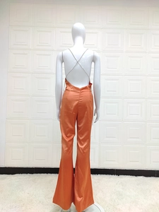 Detailed back view of orange halter jumpsuit featuring crisscross metal chain straps
