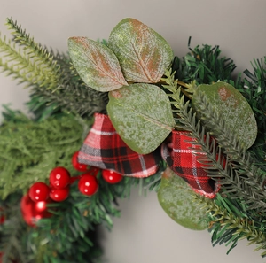 Detail of Christmas wreath with frosted eucalyptus leaves, red berries and plaid ribbon