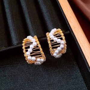 Macro detail of French vintage C-shape gold wire earrings with elegant white pearls