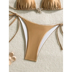 Bikini metálico dorado con adornos de estrellas de mar y braguita con lazos laterales