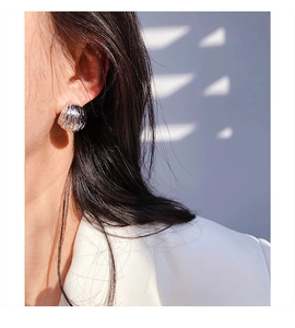 Detail of silver C-shaped hoop earring with vertical stripes on a model side view